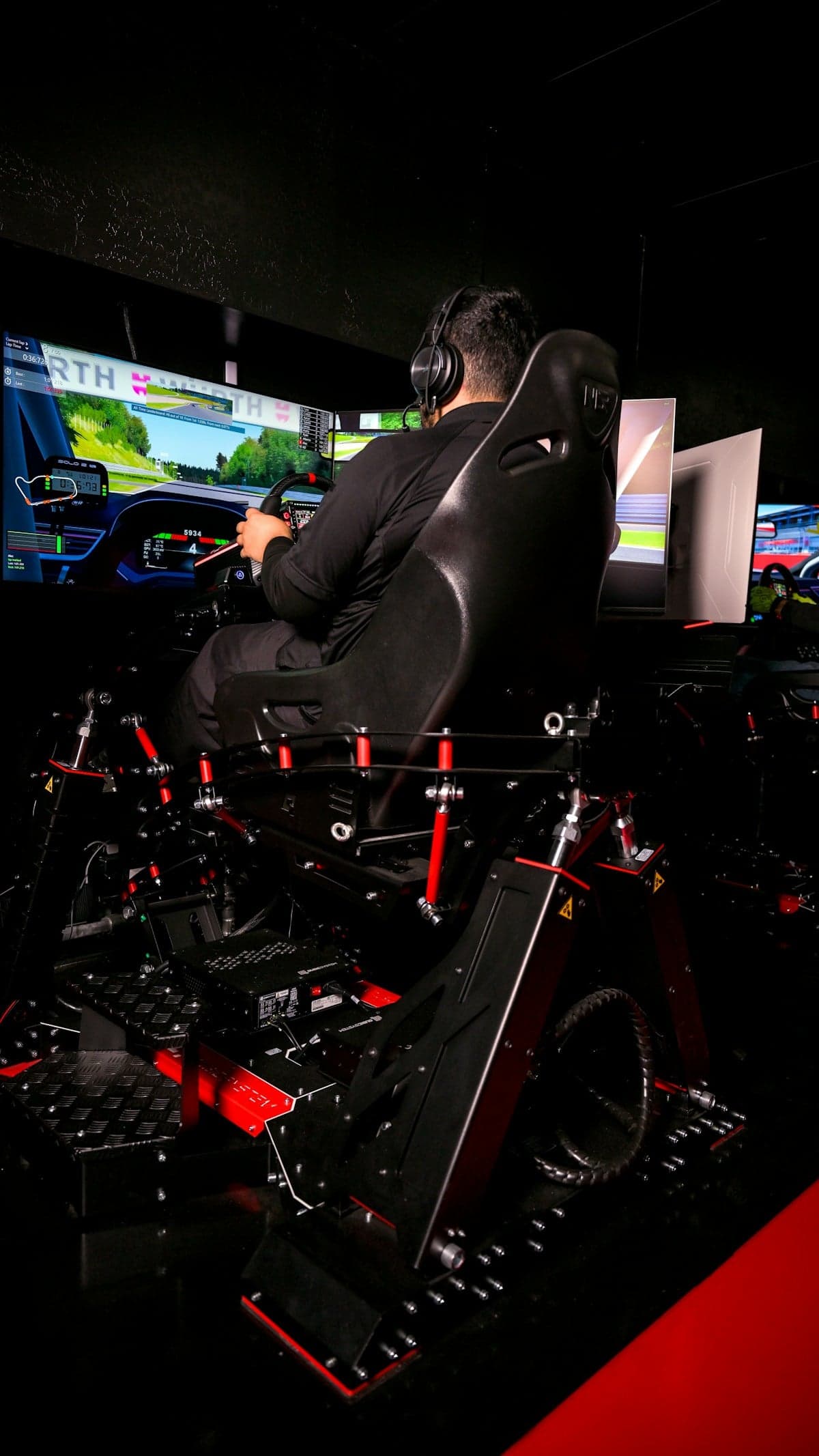 A driver using a multi-screen racing simulator cockpit, reference photography